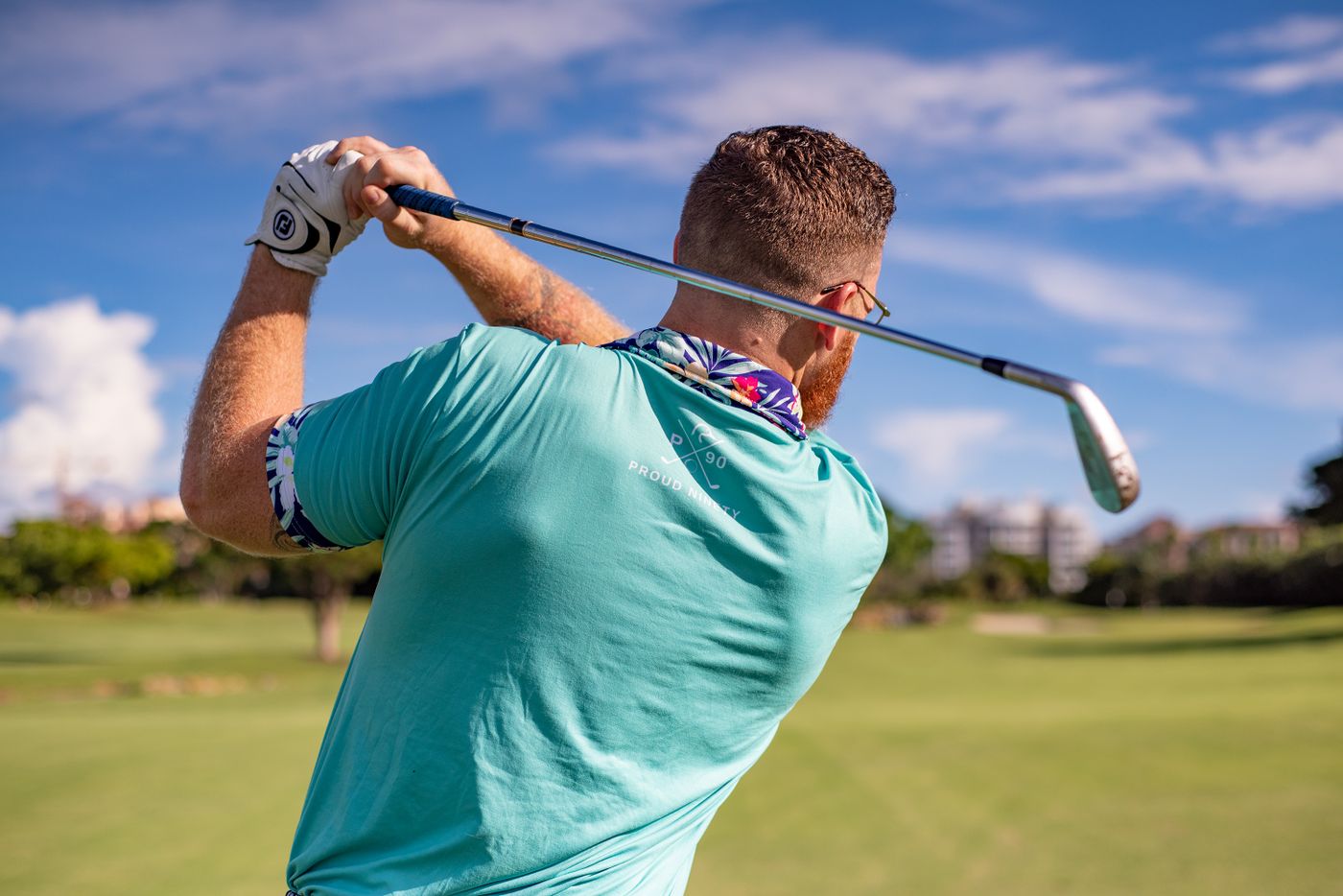 A golfer following through on a swing on a sunny course